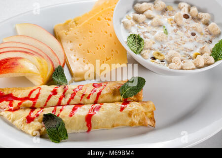 La prima colazione con frittelle di mele, formaggio e muesli con latte. Foto Stock