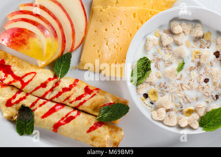 La prima colazione con frittelle di mele, formaggio e muesli con latte. Foto Stock