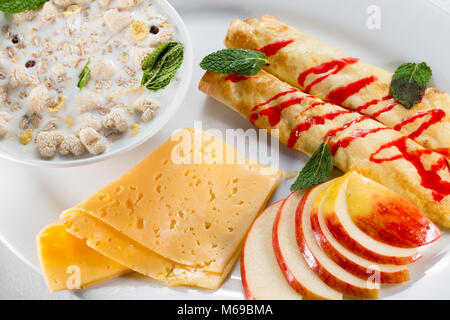 La prima colazione con frittelle di mele, formaggio e muesli con latte. Foto Stock