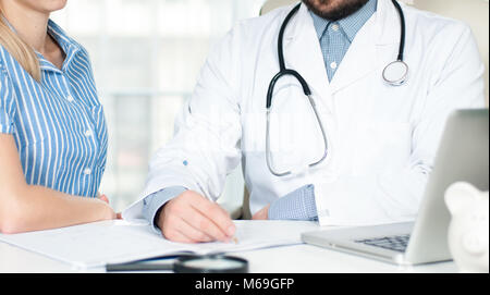 Medico sta parlando con la donna paziente e rendere note durante la seduta nel suo ufficio Foto Stock
