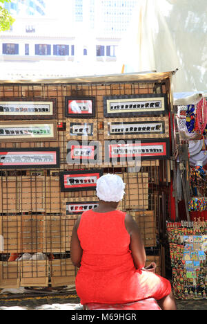 Signora locale sulla bancarella vendendo artigianato africano sulla vivace Greenmarket, una storica piazza con pavimentazione in ciottoli,, nel centro storico di Città del Capo in Sud Africa Foto Stock