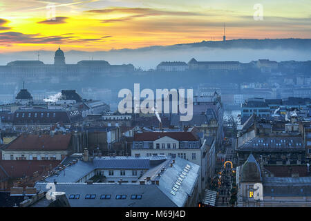 Tetti del centro di Budapest e Castello Reale nella nebbia al tramonto Foto Stock