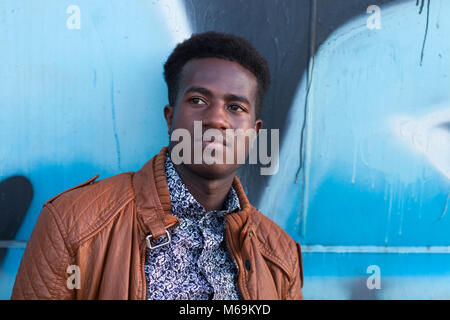 Bel giovane uomo nero nella parte anteriore del blu e nero dipinto di superficie metallica Foto Stock