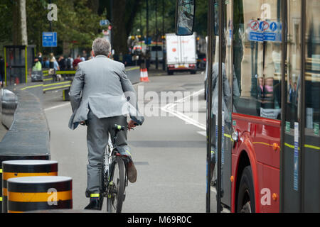 Un imprenditore in un business suit corse in bicicletta attraverso le strade di Londra. Foto Stock