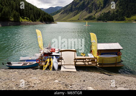 LIVIGNO, Italia - 1 agosto: Donna sul molo in legno con imbarcazioni, canoe e pedalò sul Lago di Livigno il 1 agosto 2016 a Livigno, Italia. Foto Stock