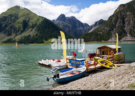 LIVIGNO, Italia - 1 agosto: Donna sul molo in legno con imbarcazioni, canoe e pedalò sul Lago di Livigno il 1 agosto 2016 a Livigno, Italia. Foto Stock