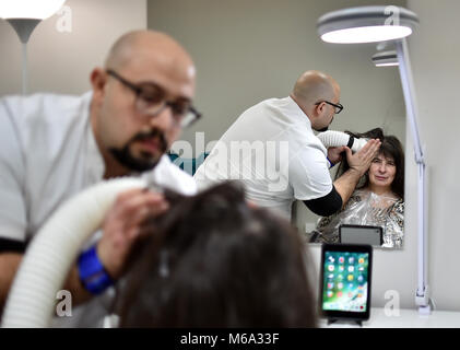 01 marzo 2018, Germania Berlino: Naram Shakra uccide i pidocchi della testa del cliente Monika Beloch al anti pidocchi salon 'Bye bye Laeuse' (lit. bye bye pidocchi) con aria calda. Foto: Britta Pedersen/dpa-Zentralbild/dpa Foto Stock