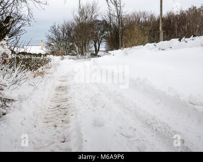 East Lothian, Scozia, Regno Unito, 2 marzo 2018. Regno Unito Meteo: il cosiddetto 'Bestia da est' artico meteo afferra il paesaggio rurale. La neve si sposta attraverso le sezioni di strada sono diversi piedi alto in luoghi, la creazione di un paese delle meraviglie invernali in scena con il pneumatico del trattore le tracce sulla strada coperta di neve Foto Stock