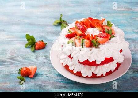 Fragole e panna pan di spagna. In casa dessert estivo blu sul tavolo di legno. Dolci per cari Foto Stock