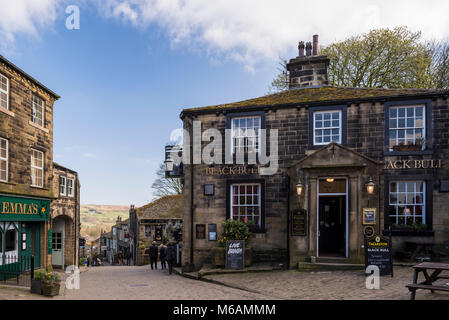 Haworth villaggio dove Bronte suore vissero, vista lungo scoscese, pittoresco, stretta strada principale, Black Bull pub in primo piano - West Yorkshire, Inghilterra, Regno Unito. Foto Stock