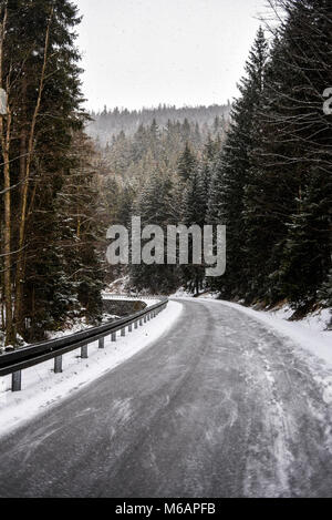 Inverno road tra le foreste di montagna. Foto Stock