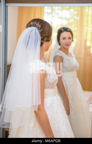 Giovane e bella sposa abito da sposa in cerca dello specchio Foto Stock