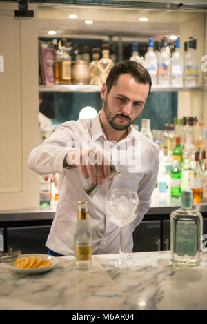 Una barra bianca uomo si mescola un gin tonic in un bar in hotel Foto Stock