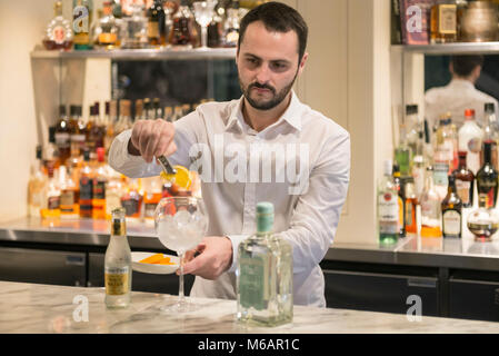 Una barra bianca uomo si mescola un gin tonic in un bar in hotel Foto Stock