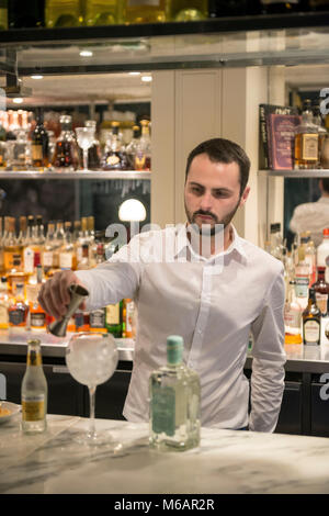 Una barra bianca uomo si mescola un gin tonic in un bar in hotel Foto Stock