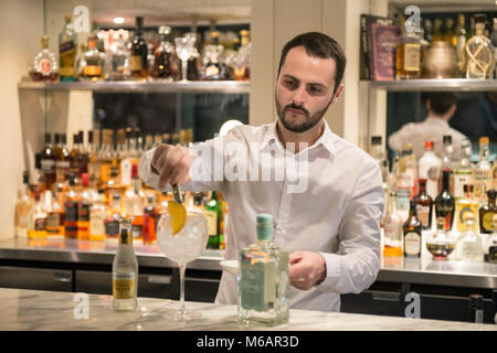 Una barra bianca uomo si mescola un gin tonic in un bar in hotel Foto Stock