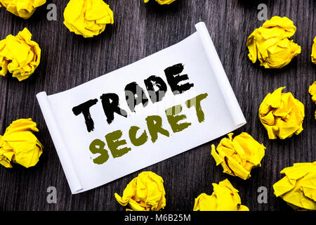 La scrittura di un testo che mostra il segreto commerciale. Il concetto di business per la protezione dei dati scritti su una nota adesiva notepad libro di notebook in legno con sfondo giallo sti Foto Stock