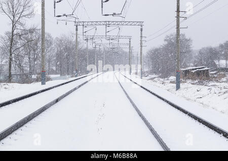 Inverno e tempesta di neve sui binari della ferrovia. Un forte vento e neve, coperto di neve e rotaie e in condizioni di scarsa visibilità Foto Stock