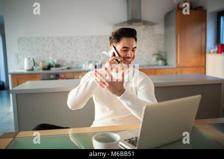 Ritratto di uomo felice di lavoro a casa parlando sul cellulare Foto Stock