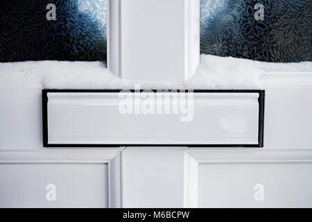 Letterbox bianco su una porta bianca, con neve. Foto Stock