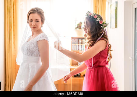 Aiutare la sposa a mettere il suo abito da sposa a Foto Stock