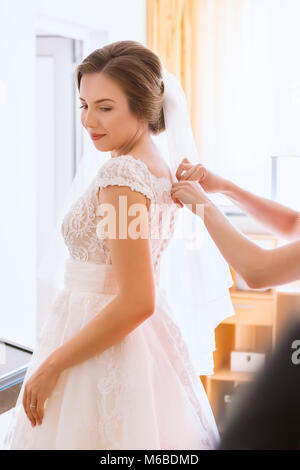 Aiutare la sposa a mettere il suo abito da sposa a Foto Stock