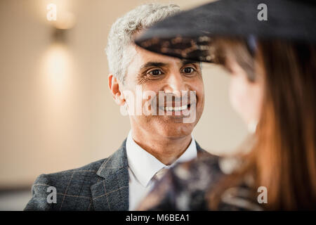 Uomo maturo è di avere una conversazione con la moglie a loro figlio del matrimonio. Ella ha il suo torna alla fotocamera e indossa un fascinator. Foto Stock