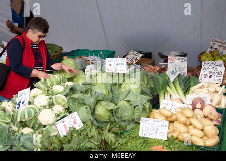 Il cliente cerca attraverso coltivati localmente produrre nel mercato a Boston, Lincolnshire, Inghilterra. Foto Stock