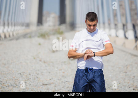 Ritratto di giovane atleta guardando al suo impulso tasso di cuore smart watch Foto Stock