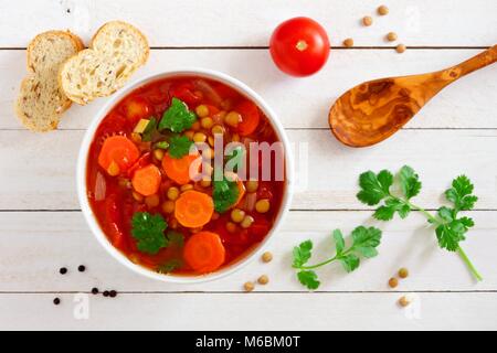 In casa di pomodoro, zuppa di lenticchie, sopra Scena su un bianco sullo sfondo di legno Foto Stock