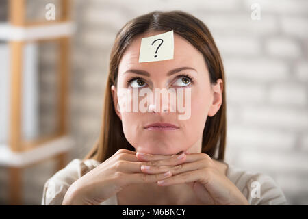 Close-up di una imprenditrice della fronte con un punto interrogativo sulla nota adesiva Foto Stock