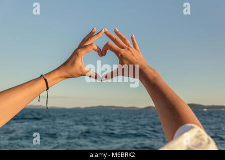 Le mani a forma di cuore contro lo sfondo del mare. Foto Stock