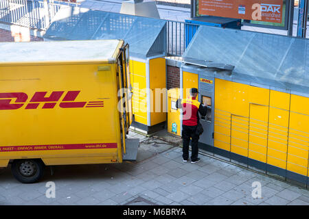 Germania, Colonia, un pacco DHL service driver fornisce un Packstation nel quartiere Deutz. Deutschland, Koeln, ein DHL beliefert Fahrer eine Packsta Foto Stock