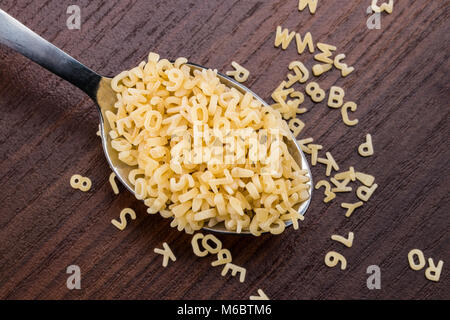 Alfabeto di pasta a cucchiaio su sfondo di legno. Foto Stock