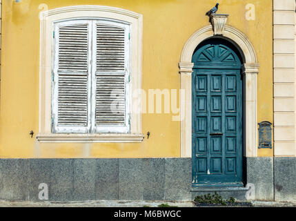 La porta verde e la finestra bianca in un antico muro giallo Foto Stock