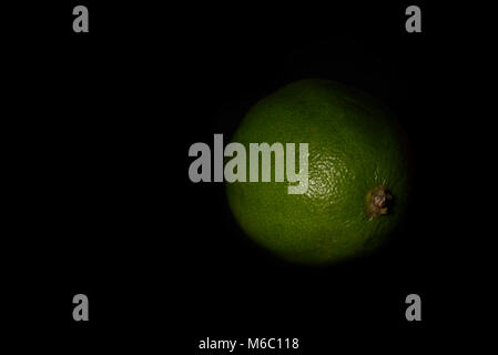 Calce verde su sfondo nero. Dark concetto di frutta Foto Stock