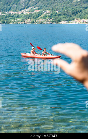 Lago d'Orta, Italia - 12 agosto 2016: Una mano sembra essere afferrando una canoa con due anziani kayak sul lago d'Orta - Lago d'Orta in Italia. Foto Stock