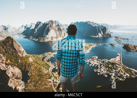 Traveler uomo in piedi sul bordo scogliera da soli il viaggio in Norvegia lifestyle outdoor avventura vacanze estive Reinebringen mountain vista aerea Lofoten i Foto Stock