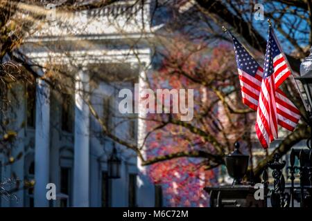 Il sole che splende su due bandiere sul recinto vicino alla Casa Bianca di Washington DC. Foto Stock