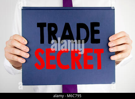 La scrittura di un testo che mostra il segreto commerciale. Il concetto di business per la protezione dei dati scritti sul libro quaderno tenendo da uomo in tuta sfondo sfocato. Foto Stock