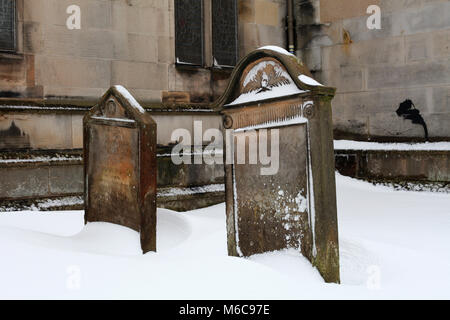 Due lapidi parzialmente coperto dalla tempesta di neve nella motivazione della vecchia chiesa parrocchiale a Corstorphine, Edimburgo Foto Stock