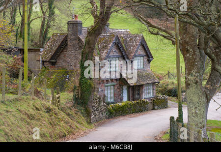 Cottage in pietra accanto a corsia nella boscosa valle nel Devon, Inghilterra Foto Stock