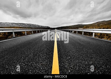 Immagine di una vasta prateria aperta e le montagne con un lastricato highway road che si allunga per quanto l'occhio può vedere con la bellissima natura sotto un cielo nuvoloso Foto Stock