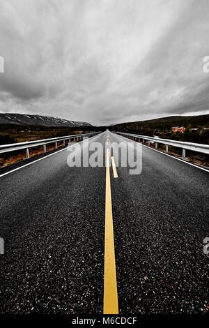 Immagine di una vasta prateria aperta e le montagne con un lastricato highway road che si allunga per quanto l'occhio può vedere con la bellissima natura sotto un cielo nuvoloso Foto Stock