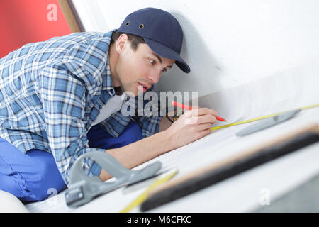 Un commerciante che stabilisce la pavimentazione in linoleum Foto Stock