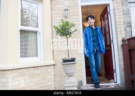 Un asiatico studente lascia la sua sistemazione degli studenti attraverso lo sportello anteriore Foto Stock