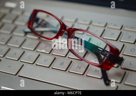 Stanco degli occhiali su un bronzo-colorata tastiera portatile Foto Stock