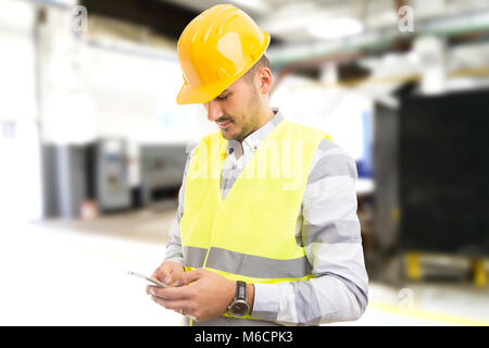 La fabbrica lavoratore dipendente navigazione chat SMS sullo smartphone durante le ore di lavoro di essere distratti dal lavoro Foto Stock