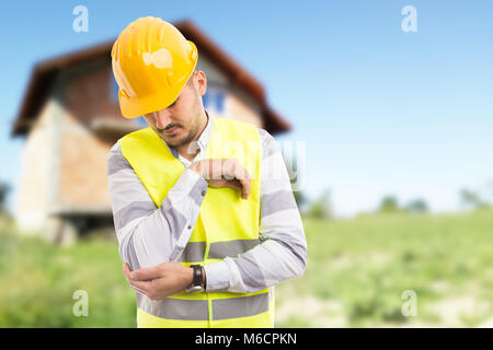 Il lavoro del pregiudizio e dolorosa concetto a gomito con builder su sfondo all'aperto con nuovi in costruzione house Foto Stock