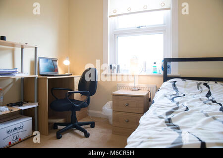 Gli studenti camere da letto in uno studente lasciare casa mentre sono stare con il proprietario, che mostra il letto e scrivania zone Foto Stock